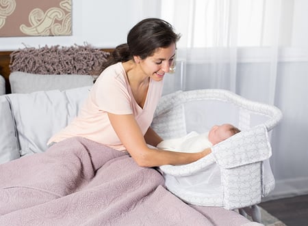 Mom lifting her infant out of the Bassinest